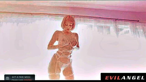 Adira Allure in seductive white lingerie harness, posing provocatively
