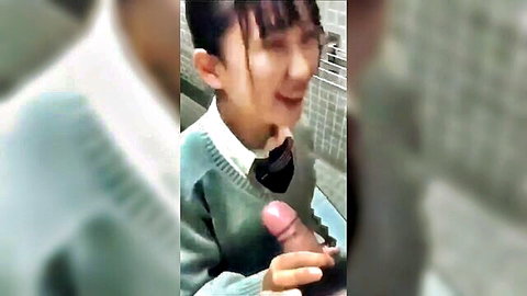 Japanese schoolgirl in uniform smiles holding thick pink cock to her masked lips in restroom
