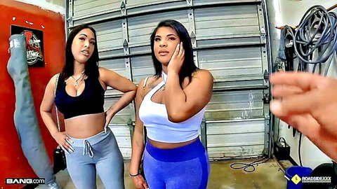 Two sexy Latinas in tight leggings and crop tops posing seductively with big asses in garage