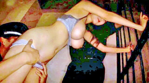 Asian babe bent over railing in gray thong, exposing big ass for threesome fun