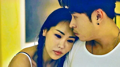 Sexy Korean babe with hoop earrings cuddles intimately against handsome guy's shoulder showing cleavage