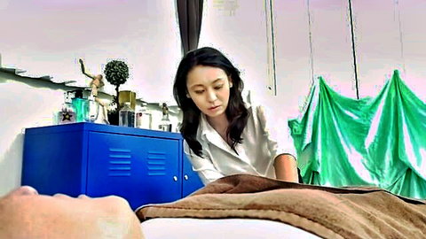 East Asian MILF masseuse in white blouse leaning over naked man on massage table