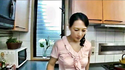 Mature Japanese wife in pink ruffled blouse in kitchen scene