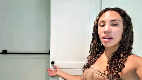 Curly-haired fit mixed woman in towel at door, muscle mommy vlog style