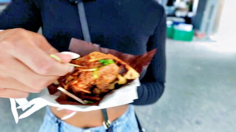 Gym girl bulking at food festival, holding stuffed waffle kebab