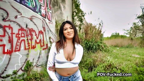 Sexy Hispanic babe in cleavage-baring crop top and jeans poses outdoors