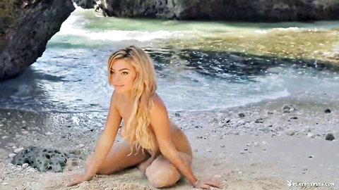 Nude blonde with big tits sitting sensually on beach smiling seductively