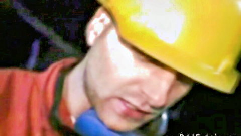 Close-up of handsome construction worker in yellow hard hat and work gear