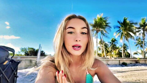 Blonde model in green bikini smiling on Miami beach selfie vlog