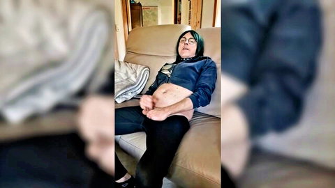 Green-haired woman lounging relaxed in blue top and black pants, exposed midriff