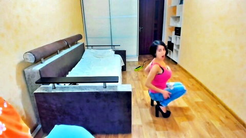 Busty brunette Myla Angel squatting in pink top, jeans, and high heels