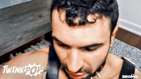 Submissive bearded mature man in leather collar and leash stares intently during gay fetish scene