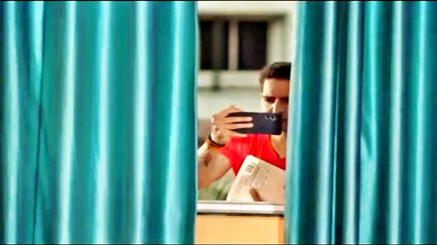 Indian man in red shirt taking selfie behind teal curtains, Pehredaar hot series