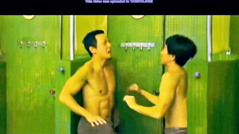 Two muscular Asian men in playful ball grab, shirtless and toned