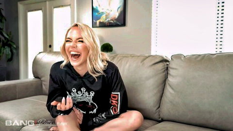 Blonde pornstar Kelsey Kane laughing in black hoodie playfully