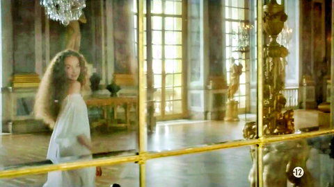 Alexia Giordano in elegant off-shoulder white gown, curly hair in luxurious hall