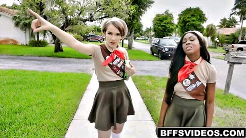 Two sexy teens in girl scout uniforms with short skirts pointing playfully outdoors