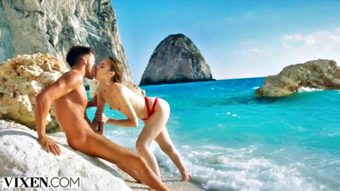 Blonde in red thong performs oral on nude muscular man on rocky beach vacation sex