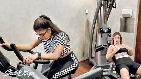 Two fit women in sportswear working out in gym, lesbian tease