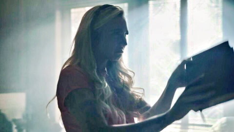 Blake Blossom reading book in soft light, tattooed blonde with curves