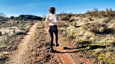 Fit woman in tight leggings running on woodland trail, outdoor jog tease