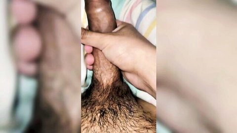 Close-up of LucasUBA's big black cock gripped by hand in gay scene under sheets