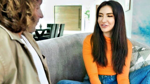 Jane Wilde in orange top chatting on couch, cute feet focus