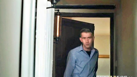 Handsome man in light blue shirt stands in doorway gazing intensely