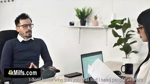 Office boss in sweater talks with Asian assistant holding papers