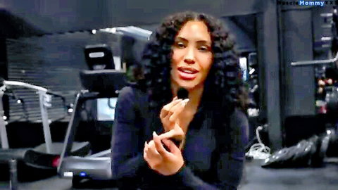 Curly-haired fit woman gesturing in black top during gym push workout
