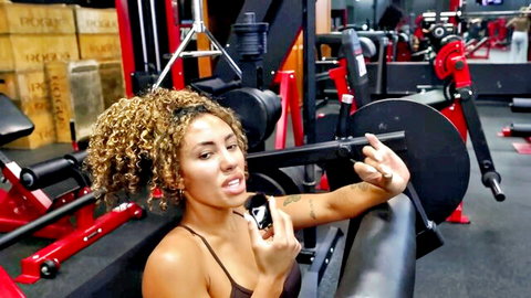 Fit curly-haired gym babe teases with tongue out selfie showing deep cleavage and toned abs