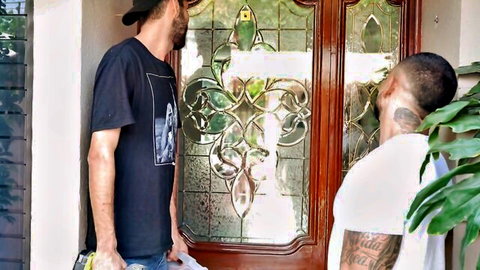 Two tattooed muscular men in t-shirts stand at ornate stained glass door entrance
