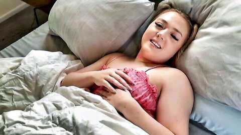 Eva Nyx in pink ruffled lingerie, seductive smile on bed