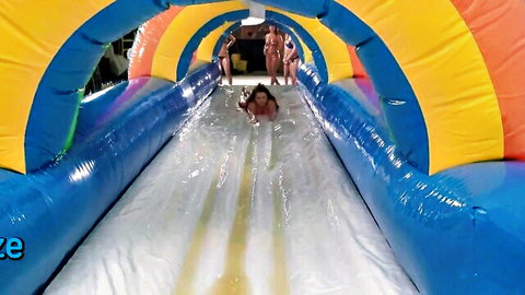 Group of bikini MILFs sliding down wet inflatable water slide outdoors