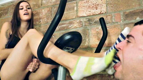 Brunette on exercise bike gets sweaty striped knee sock foot sucked by eager guy
