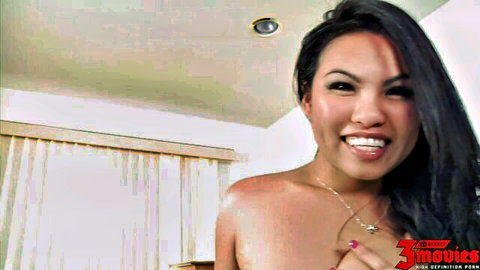 Smiling Asian beauty with perky bare tits posing topless in bedroom