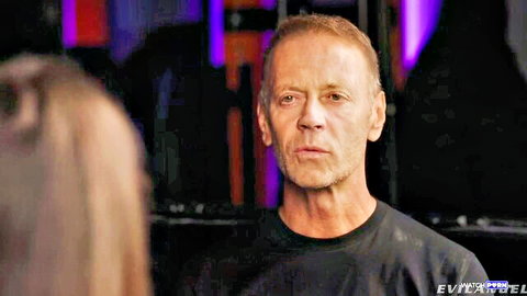 Man intensely stares at long-haired woman in dark club under purple lights