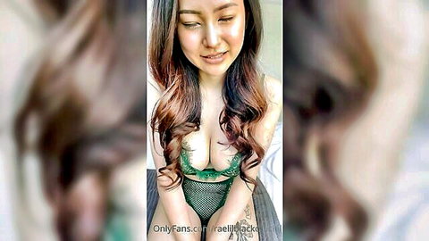Asian beauty with massive tits spilling from green lace bra smiles seductively