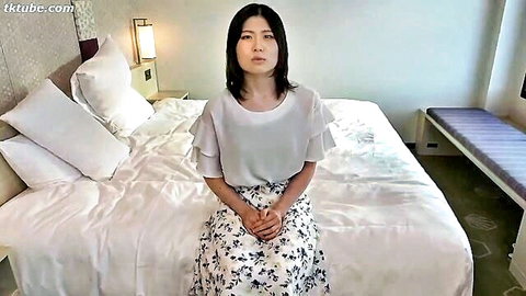 Japanese woman in white blouse and floral skirt sitting poised
