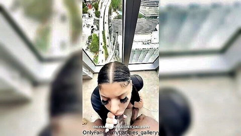 Curvy Black woman in black dress teasing blowjob pose near city view