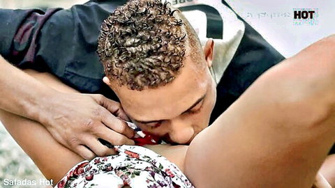 Curly-haired man intimately kissing woman's exposed thighs in floral dress