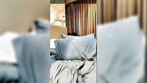 Blurry bedroom setup with gray pillows and sheets, teasing Thai pale pussy reveal