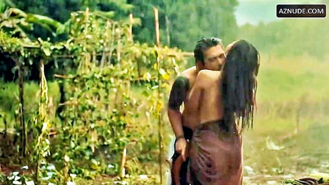 Tattooed man embraces wet Filipina beauty in passionate outdoor kiss