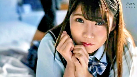 Cute Japanese schoolgirl in sailor uniform pouting on bed with clasped hands and sexy legs