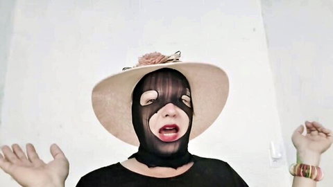 Mysterious masked woman in floral hat and black top, gladiator queen pose