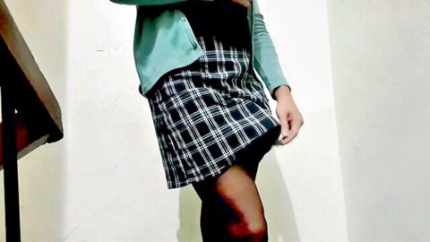 Trans woman in green cardigan, black plaid skirt and stockings teases outdoors
