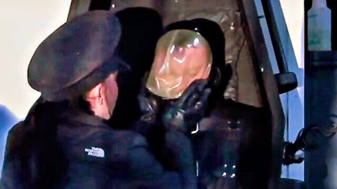 Kinky man in black uniform with plastic bag over head in suffocation fetish play