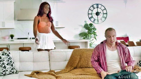Ana Foxxx in orange top and white skirt approaches man on couch