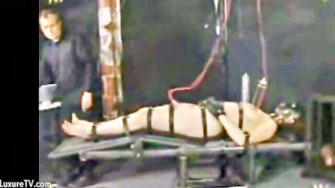 Bound nude woman in BDSM milking session with tubes and straps