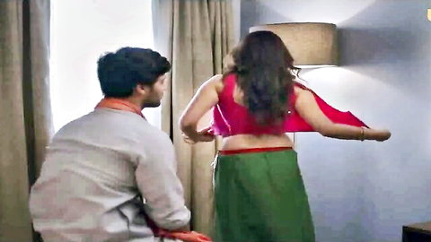 Indian woman in red blouse and green skirt, man behind her in intimate pose